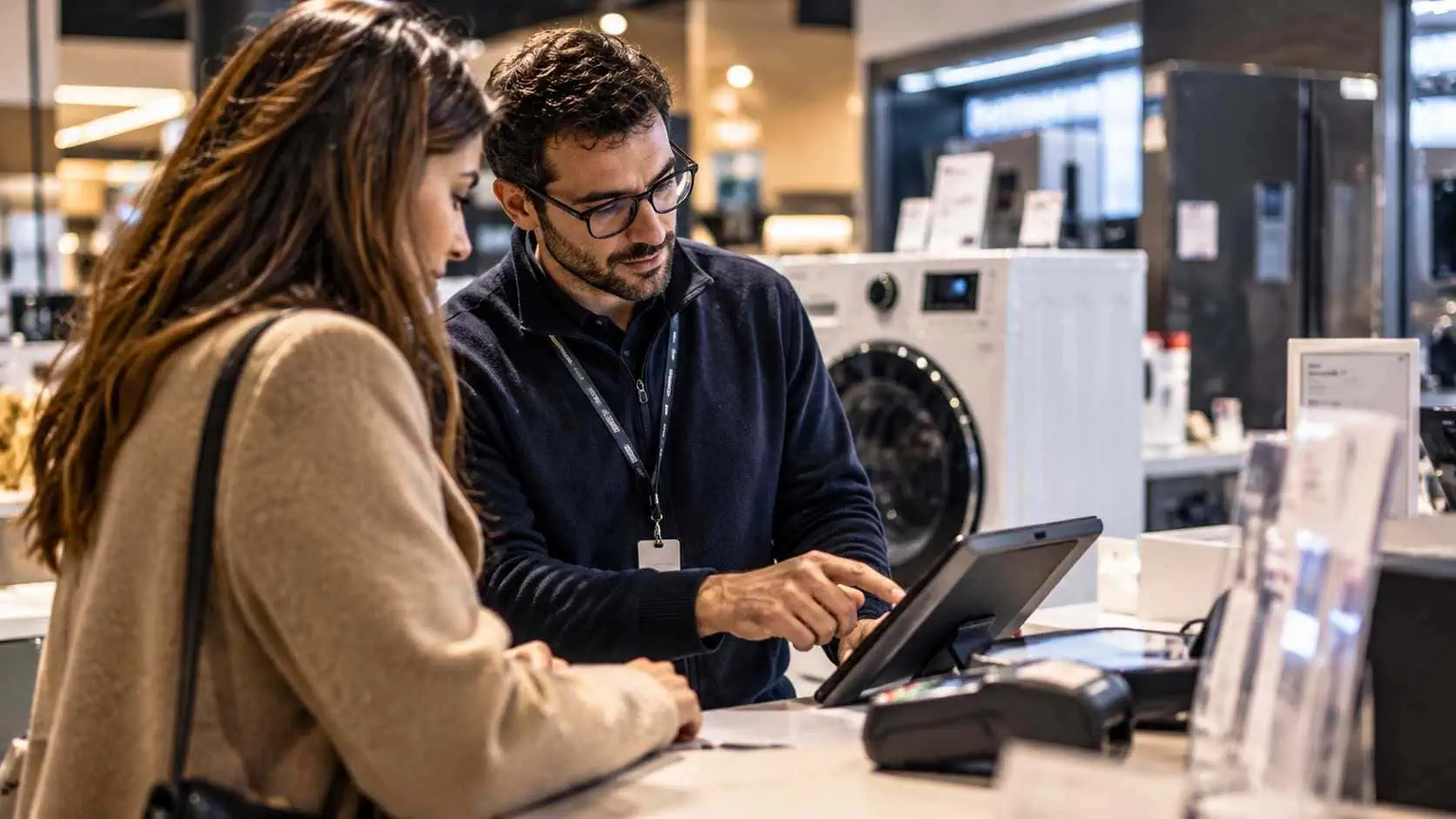 Cliente e addetto in un punto vendita di elettrodomestici consultano su tablet una soluzione di credito al consumo.