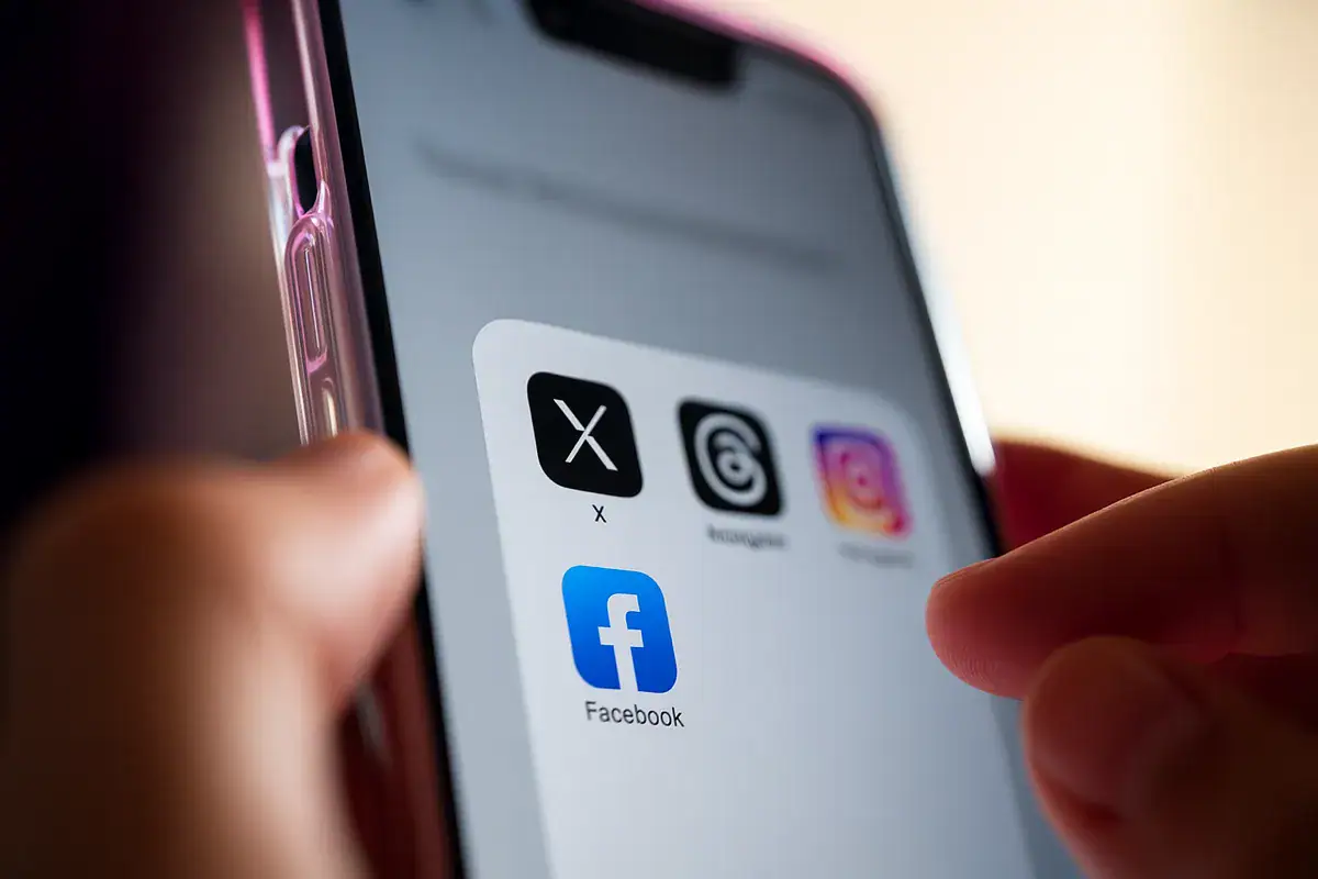 Account Meta bloccato su smartphone con icone Facebook, Instagram e X mentre un utente tenta di accedere dall’app mobile.